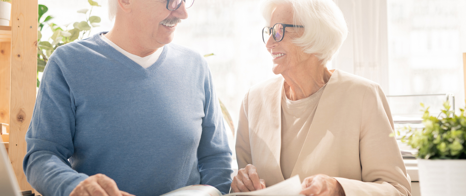 Older man and woman smiling while looking at an information guide