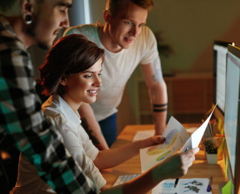 Young casually dressed business people looking at computer screen